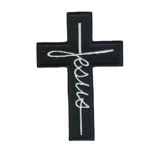 May include: Black embroidered iron-on patch with a white cross and the word "Jesus" written in a cursive script.