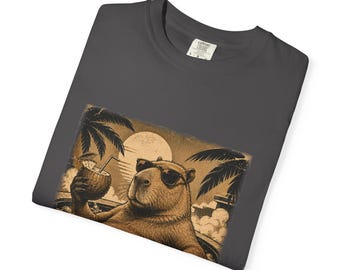 May include: A charcoal gray t-shirt featuring a graphic print of a capybara wearing sunglasses, relaxing in a pool with a coconut drink. The illustration includes palm trees and a large sun in the background, rendered in a sepia-toned artistic style.
