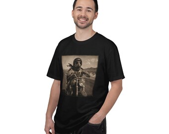 May include: A black short-sleeved t-shirt featuring a sepia-toned graphic print on the chest. The graphic depicts a turtle wearing a vintage leather helmet and goggles, riding a motorcycle along a desert road under a cloudy sky.