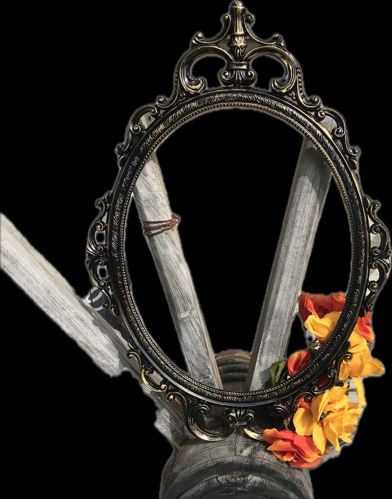 Puede incluir: Marco de fotos ovalado y ornamentado con acabado bronce oscuro. El marco est&aacute; decorado con intrincados adornos y se apoya sobre una base de madera r&uacute;stica. Flores naranjas y amarillas adornan la base, a&ntilde;adiendo color.