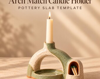 May include: A ceramic arch match candle holder with a speckled green and cream glaze. The piece features a central candle socket holding a lit cream taper candle and a side compartment containing wooden matches. Text reads Arch Match Candle Holder.