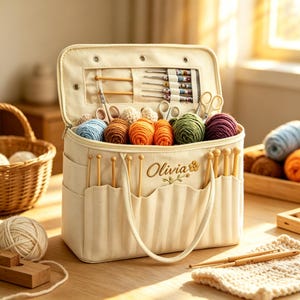 May include: A cream-coloured canvas yarn storage bag featuring the name Olivia embroidered on the front. The bag is filled with various colourful yarn balls, knitting needles, and crochet hooks stored in interior pockets and exterior slots.