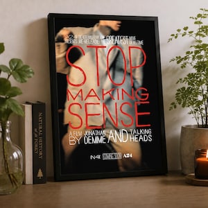 May include: A framed movie poster for Stop Making Sense, featuring a blurred figure in a light-colored suit. The text reads: A24 THE 40TH ANNIVERSARY OF THE GREATEST MOVIE OF ALL TIME, STOP MAKING SENSE, A FILM BY JONATHAN DEMME AND TALKING HEADS, IN 4K.