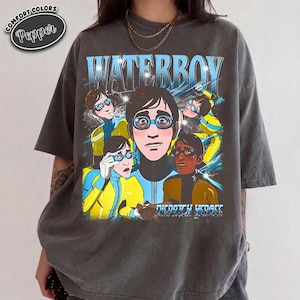 May include: A charcoal gray short-sleeve t-shirt featuring a graphic print with the text WATERBOY and DISPATCH HEROES. The design displays multiple figures wearing blue and yellow outfits with goggles, set against a dark, starry background.
