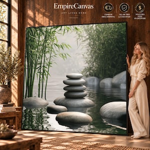 Pode incluir: Uma grande tela retangular apresentando uma pilha de cinco pedras cinzentas lisas equilibradas em água calma, rodeadas por caules de bambu verde e névoa suave. A obra de arte tem o título EmpireCanvas Art Lives Here no topo central.