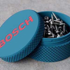 May include: A round, blue, textured storage container with a knurled exterior surface. The lid features the word BOSCH in red capital letters. The container is open, revealing a collection of silver-coloured metal screws inside the basin.