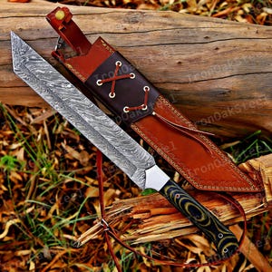 May include: A fixed-blade knife with a patterned Damascus steel blade and a dark green and black layered handle. The knife is accompanied by a brown leather sheath featuring a decorative lace-up design with white cord and a brass snap closure.