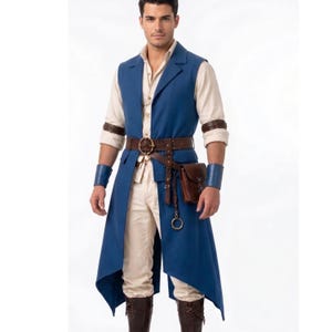 May include: A long blue sleeveless vest worn over a cream-colored button-down shirt and trousers. The outfit includes a brown leather belt with a pouch, a metal ring attachment, brown leather arm cuffs, and brown leather boots.