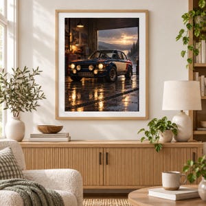 May include: A framed wall art print depicting a blue and white rally car parked inside a garage with its headlights on. The car is positioned on a wet floor reflecting the lights, with an open garage door revealing a sunset landscape in the background.