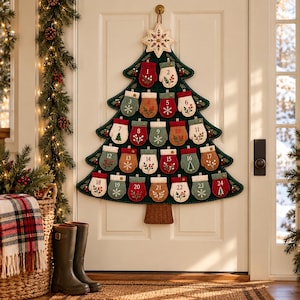 Puede incluir: Un calendario de Adviento de pared hecho de fieltro verde oscuro con forma de árbol de Navidad, que incluye veinticuatro pequeñas manoplas numeradas en tonos rojo, verde y tostado. Cada manopla tiene motivos botánicos bordados.