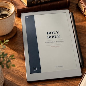 May include: A digital e-reader displaying the text Holy Bible, World English - King James, Parallel Edition, Public Domain. The device features a dark blue vertical sidebar with a letter D and is accompanied by a black stylus pen.