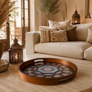 Peut inclure: Un plateau de service rond en bois avec un intérieur sombre orné d'un motif géométrique complexe de style mandala dans des tons de bleu, rouge et blanc. Le plateau présente un bord brun poli et deux poignées découpées intégrées sur les côtés.