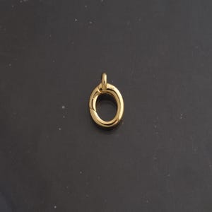 May include: A polished gold-tone oval spring gate ring clasp featuring a smooth, reflective metallic surface and a hinged mechanism for opening and closing, designed for jewelry making and connecting various chain components.