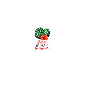 May include: A die-cut sticker featuring a green monstera leaf with a vibrant red hibiscus flower centered on it. Below the botanical illustration, the text reads Sober Grateful Unstoppable in a combination of red and black script and serif fonts.