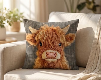 Peut inclure: Un coussin carré orné d'une illustration détaillée et texturée d'une vache Highland avec un long pelage roux ébouriffé, des cornes proéminentes et un museau rose pâle, sur un fond en tissu gris foncé rappelant le lin.