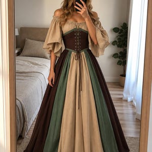 Puede incluir: Un vestido largo hasta el suelo con escote de hombros descubiertos y mangas anchas, un corpiño estilo corsé de color marrón oscuro con cordones frontales y una falda de paneles con secciones verticales alternas de tela beige, verde salvia y marrón.