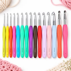 Puede incluir: Un juego de catorce ganchillos con mangos ergonómicos de colores y puntas de metal plateado. Cada mango tiene impresa su medida específica, que va de 2,0 mm a 8,0 mm. Los ganchillos están dispuestos en fila, mostrando un espectro de colores que incluye amarillo, naranja, rosa, azul, verde, morado, marrón y azul claro.
