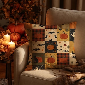 May include: A square throw pillow featuring a patchwork design with alternating squares of orange, black, and tan. The pattern includes illustrations of pumpkins, black cats, bats, ghosts, and stars, along with sections of plaid and solid colors.