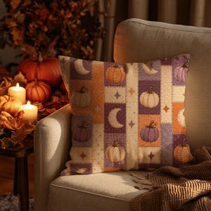 Peut inclure: Un coussin carré avec un motif patchwork composé de bandes verticales dans des tons orange, violet et crème. Le design présente des illustrations de citrouilles, de croissants de lune et d'étoiles à quatre branches sur le tissu.
