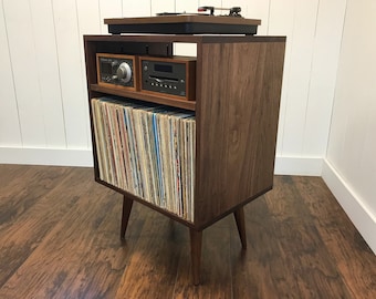 May include: A walnut wood record player stand with a turntable, amplifier, and CD player on the top shelf. The bottom shelf holds a collection of vinyl records.