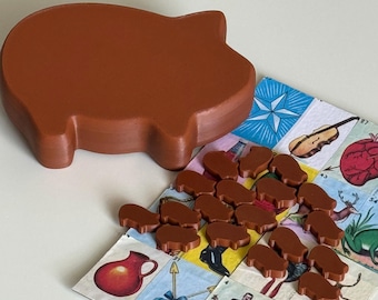 Puede incluir: Un recipiente grande de madera con forma de cerdo marrón junto a una colección de pequeñas piezas de juego a juego con forma de cerdo. Estos elementos están dispuestos sobre un tablero de juego colorido que presenta varios iconos ilustrados.
