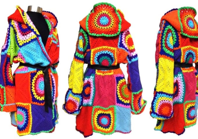 May include: A colorful, hooded crochet robe with a patchwork design. The robe features a variety of bright colors, including red, orange, yellow, green, blue, and purple. It has long sleeves and a black belt. The robe is displayed on a mannequin.