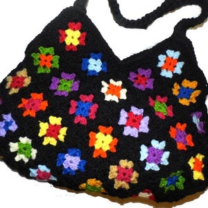 May include: A black crocheted bag with a colorful granny square pattern. The bag has a long strap and is made with a variety of colors, including red, blue, green, yellow, and orange.