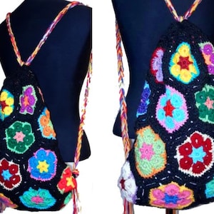 以下が含まれることがあります： カラフルな花の模様が施された黒い編み物のバックパック。バックパックには、長くカラフルなストラップが付いています。