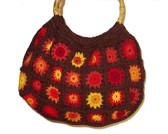 May include: A brown crocheted tote bag with a wooden handle. The bag is decorated with colorful crocheted flowers in shades of red, orange, and yellow.