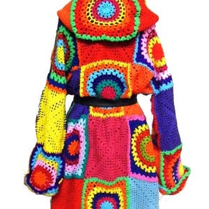 May include: A vibrant, handmade crochet coat featuring a patchwork design. The coat showcases a spectrum of colors, including red, orange, yellow, blue, and green. It has a hooded design and a fitted waist, creating a unique and eye-catching garment.