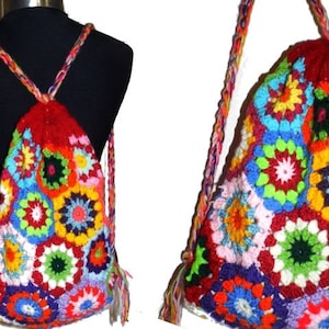 以下が含まれることがあります： 引き紐で閉じるカラフルな編み物バックパック。バックパックは、赤、ピンク、青、緑、黄、オレンジの様々な色合いの複数のおばあちゃんスクエアで作られています。