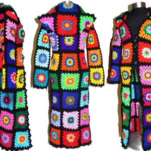 May include: A long, hooded cardigan crocheted in a patchwork pattern of colorful squares. The cardigan has a black background with squares in shades of red, orange, yellow, green, blue, purple, and pink. The cardigan is tied with a black ribbon at the front.