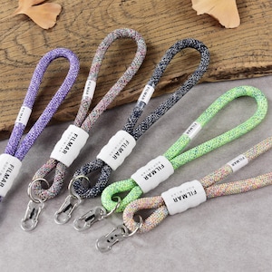 May include: Five rope lanyards in purple, multicolored, black, neon green, and pastel speckled patterns. Each lanyard features a white plastic connector labeled FILMAR, a looped cord design, and a silver metal lobster clasp at the bottom end.