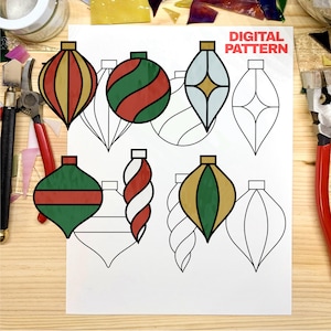 May include: A digital pattern printed on white paper featuring various Christmas ornament shapes. Some ornaments are colored in red, green, and gold, while others are black and white line drawings. The text DIGITAL PATTERN is visible.