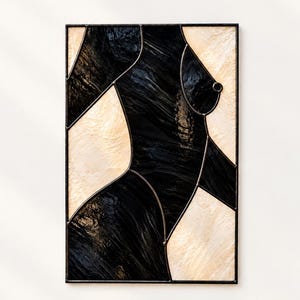 May include: A rectangular stained glass panel featuring an abstract human torso silhouette. The design is composed of textured black and cream-coloured glass pieces joined by dark metal solder lines, creating a high-contrast geometric composition.