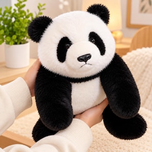 May include: A plush panda toy featuring a soft white body with black patches around the eyes, black ears, and black limbs. The stuffed animal has a realistic facial expression with dark eyes and a black nose, crafted from fuzzy material.