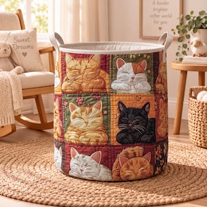 May include: A cylindrical fabric storage basket featuring a quilted patchwork design of various sleeping cats in shades of orange, black, white, and brown. The basket has two sturdy top handles and a cream-colored interior lining.