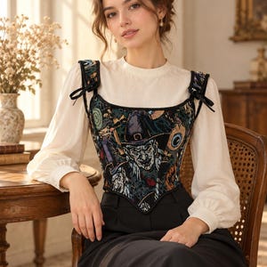 Top a corsetto nero con stampa multicolore, orlo a punta, spalline con fiocco, bustier con lacci.