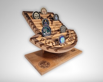 May include: Wooden display stand with slots for holding challenge coins. The stand is shaped like a military insignia and features the text "Defend Freedom For Us All".