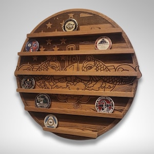 Puede incluir: Un expositor de pared redondo de madera con cinco estantes para exhibir monedas de desaf&iacute;o. El expositor presenta una imagen tallada de un submarino y dos delfines. El expositor est&aacute; hecho de madera oscura con veta de madera natural.