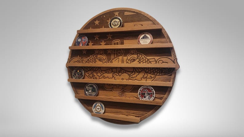 Puede incluir: Un expositor de pared redondo de madera con cinco estantes para exhibir monedas de desaf&iacute;o. El expositor presenta una imagen tallada de un submarino y dos delfines. El expositor est&aacute; hecho de madera oscura con veta de madera natural.