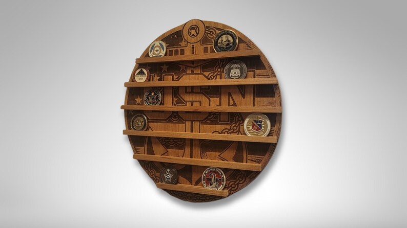 Puede incluir: Un expositor de monedas redondo de madera con un ancla y las letras USN grabadas en &eacute;l. El expositor tiene seis estantes para guardar monedas. Hay varias monedas en los estantes.