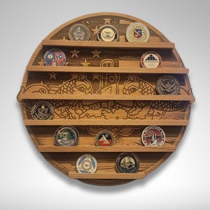 Puede incluir: Un expositor de monedas redondo de madera con una imagen tallada de dos delfines y una bandera estadounidense. El expositor tiene seis estantes para guardar monedas.