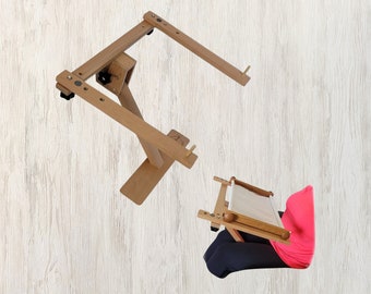 May include: A wooden embroidery stand with adjustable height and a swiveling arm. The stand has wheels for easy movement. The stand is shown with a piece of fabric stretched on the frame.