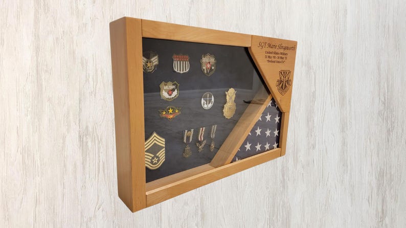 May include: A wooden shadow box display case with a framed American flag and military medals and patches. The text "SGT Mary Granados" is engraved on the wood.