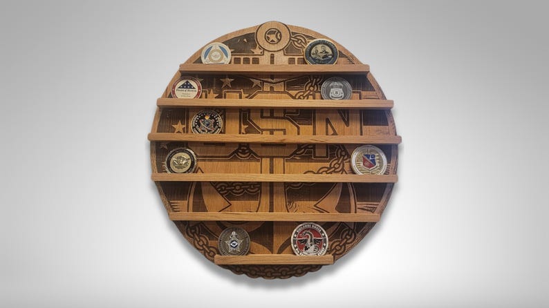 Puede incluir: Un expositor de monedas redondo de madera con un ancla grabada y las letras "USN". El expositor tiene cinco estantes para guardar monedas de desaf&iacute;o.