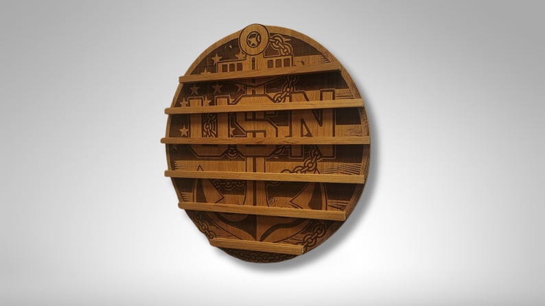 Puede incluir: Una placa redonda de madera con un dise&ntilde;o grabado con l&aacute;ser de un ancla, las letras "USN" y estrellas. La placa tiene cinco ranuras para exhibir medallas u otros art&iacute;culos.
