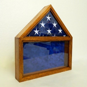 May include: A wooden flag display case with a glass front and a folded American flag inside. The case is stained a dark wood color and has a triangular top.