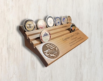 May include: Wooden coin display with a sloped design, featuring a personalized inscription for "Captain John T. Clark" and a world map with an American flag. The display holds seven challenge coins.