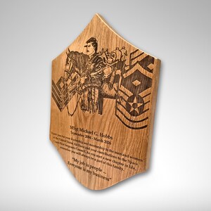 Pu&ograve; includere: Targa in legno dalla forma unica, con un'illustrazione incisa di una persona a cavallo e insegne militari. La targa include testo inciso con un nome e delle date. Il legno ha una venatura naturale.